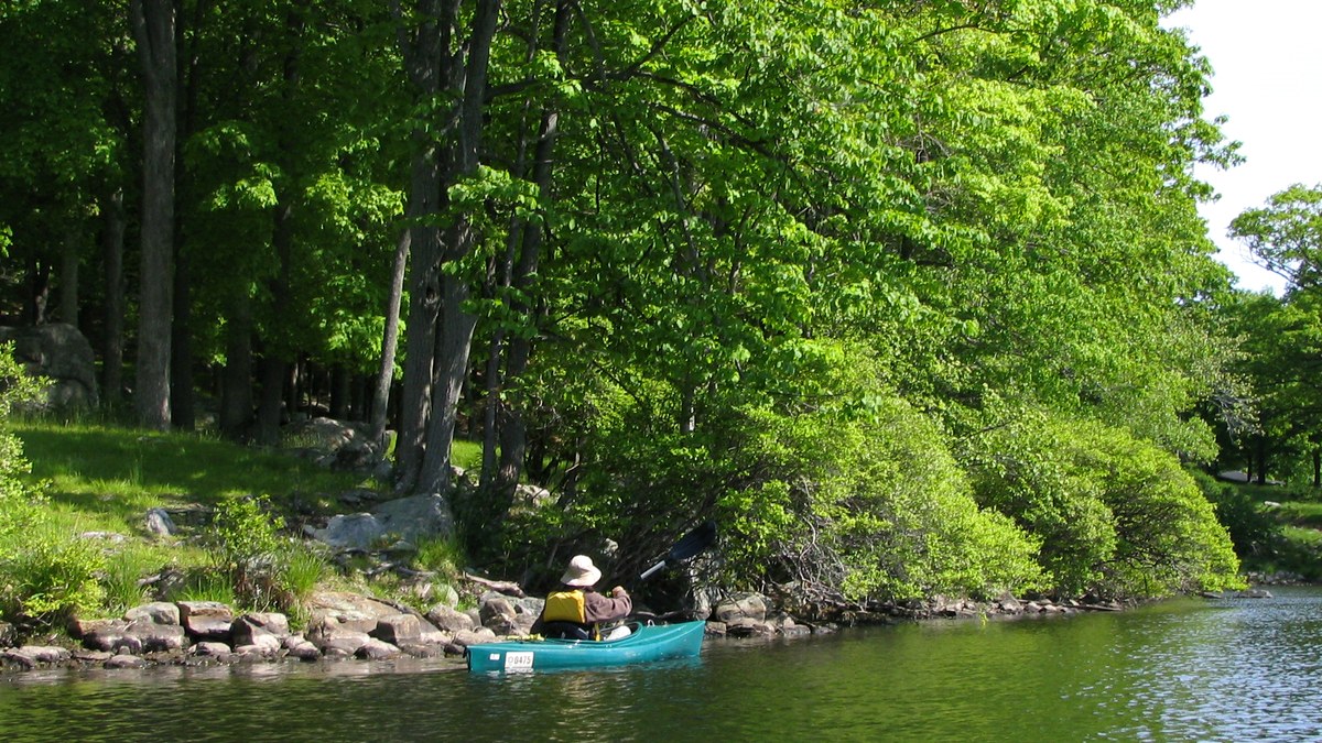 Kayak de loisir sur une rivière calme bordée d’arbres