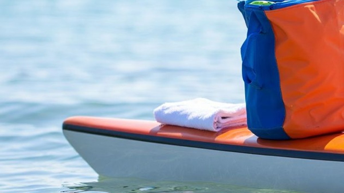 Sac étanche coloré posé sur un kayak au bord de l’eau