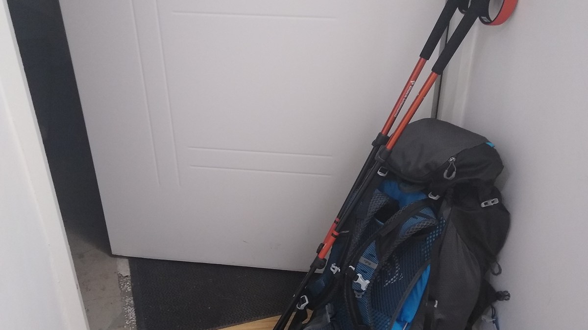 Bâtons de randonnée posés sur un sentier avec sac outdoor en arrière-plan
