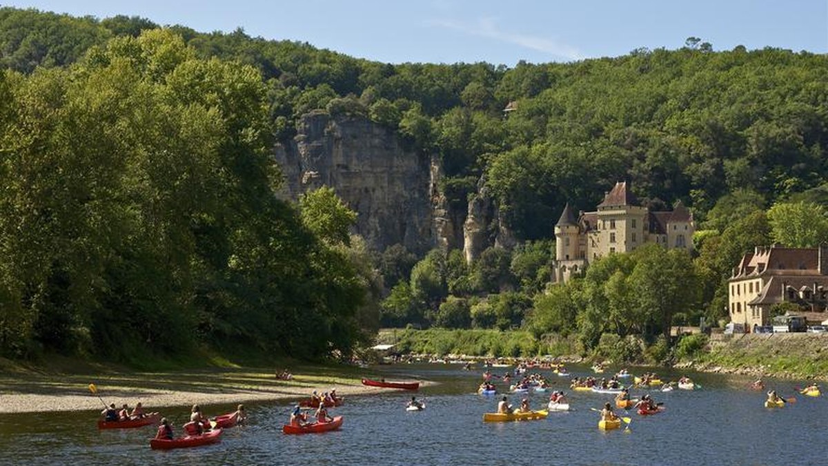 Canoës sur la Dordogne près de La Roque-Gageac avec falaises et château en arrière-plan
