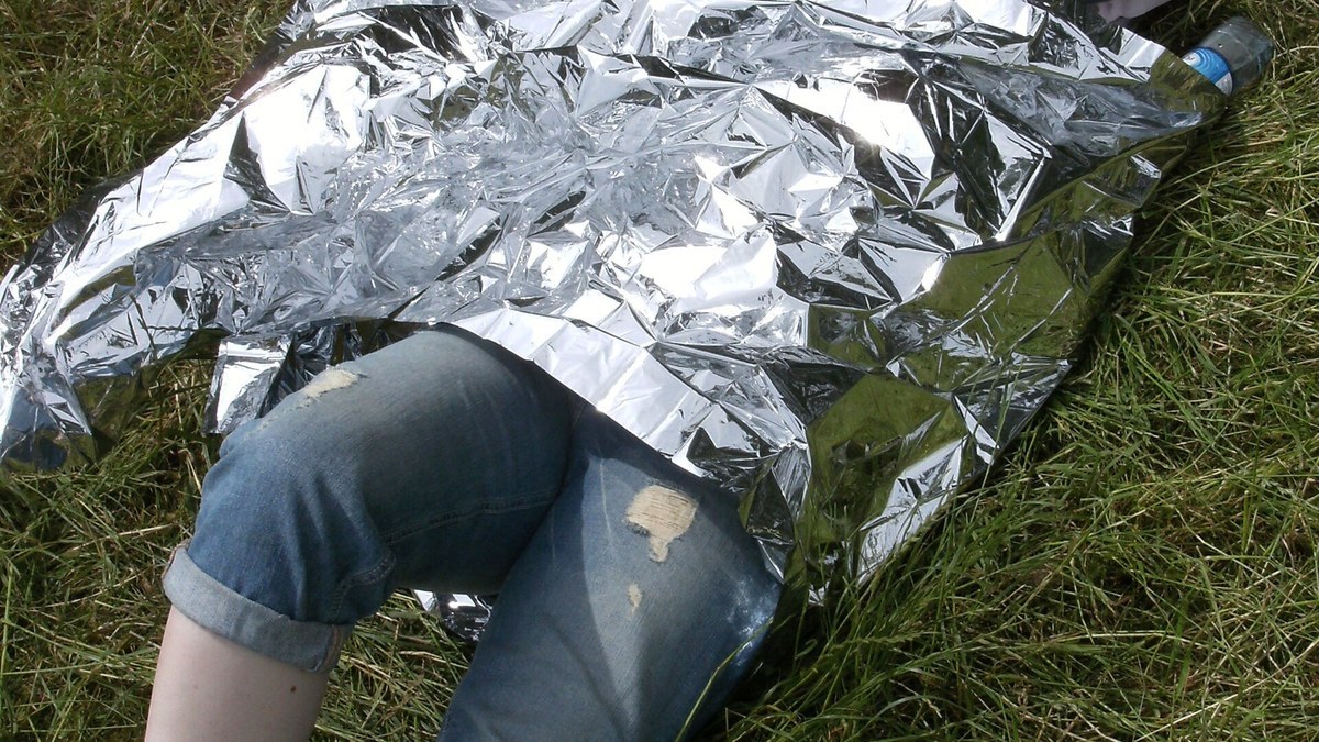 Couverture de survie ouverte avec trousse de secours et sac de randonnée sur un sentier