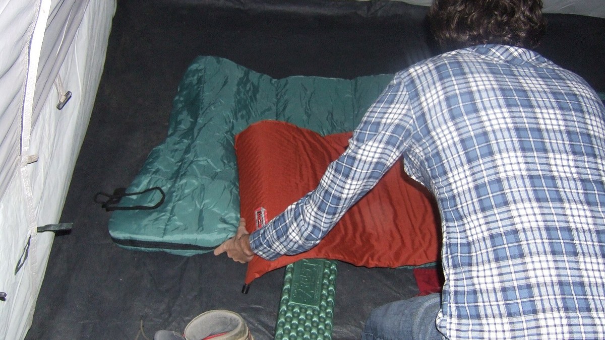 Matelas de bivouac et sac à dos dans une tente de randonnée au coucher du soleil