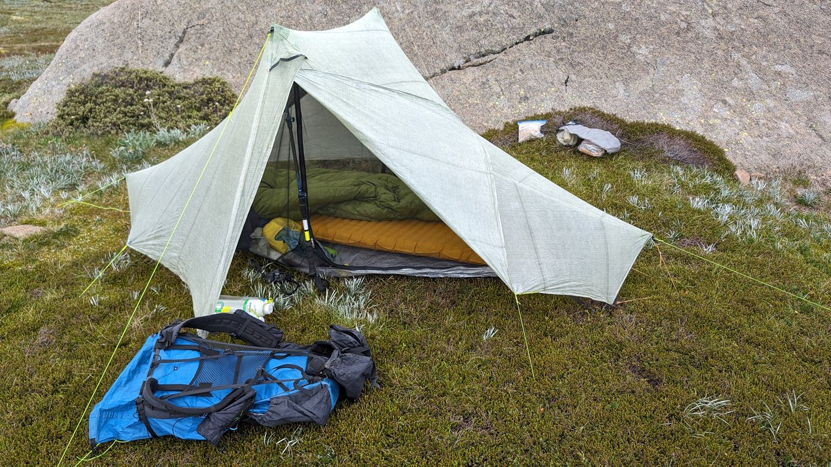 Sac de couchage installé sous une tente de bivouac avec sac à dos